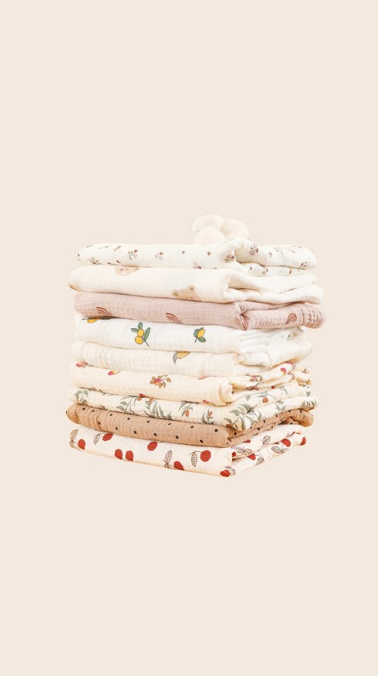 Stack of folded baby clothes on a beige background
